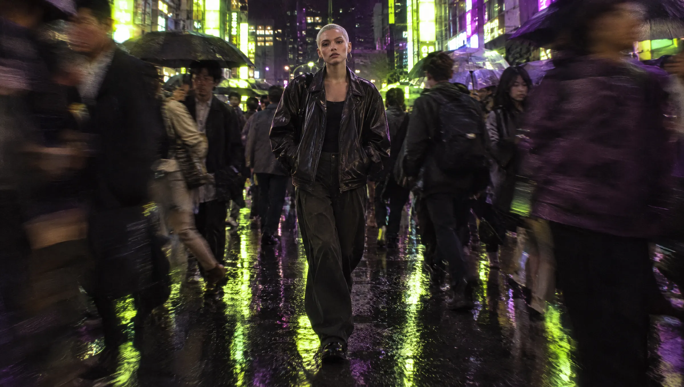 A young woman walks through a crowded crosswalk at night as the crowd steps aside to make way for her