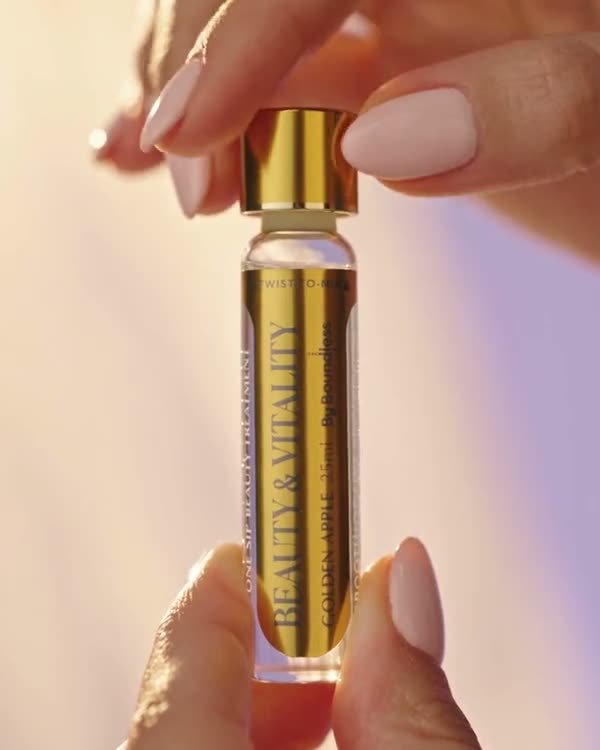 Fingers twisting the gold cap of a Longevity Shot